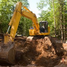 A excavator on a construction site with surrounding trees near Paoli, PA.